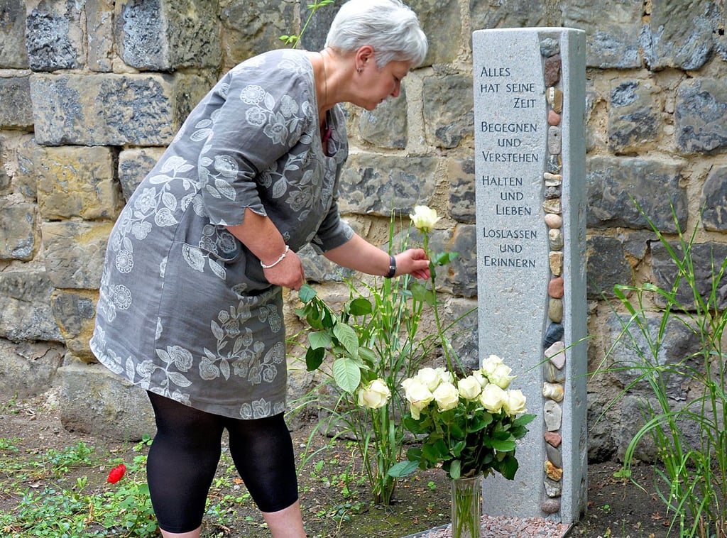 Für jeden Corona-Verstorbenen der Einrichtung eine weiße Rose - Heimleiterin Ramona Ibe am Gedenkort im Park des Seniorenzentrums Nord in Halberstadt.
