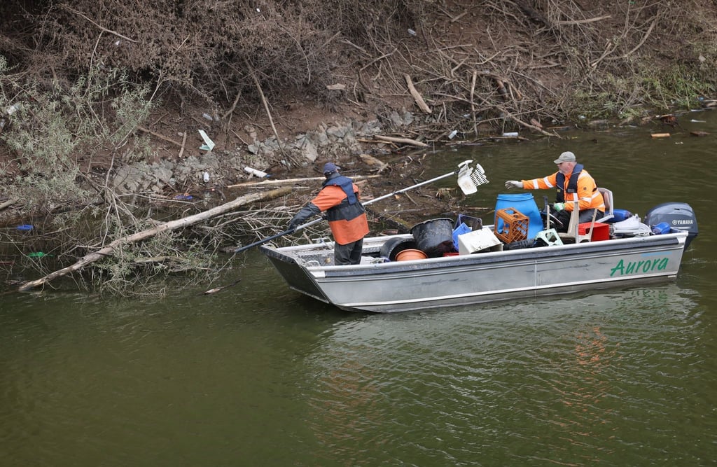 Mitarbeiter vom Wasserverband Eifel-Rur (WVER) sammeln im Nationalpark Eifel an einem Seitenarm des Urftsees Müll ein.