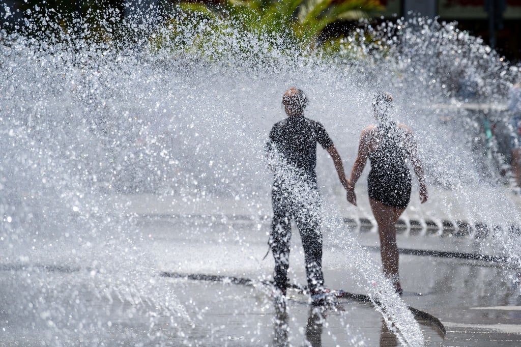 Zwei Jugendliche kühlen sich an einem Springbrunnen am Karlsplatz (Stachus) in München ab.
