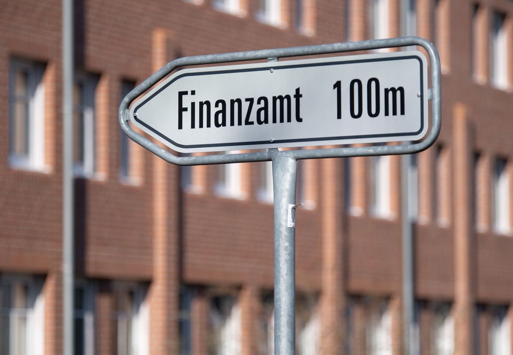 Ein Schild weist den Weg zum Eingang eines Finanzamtes.