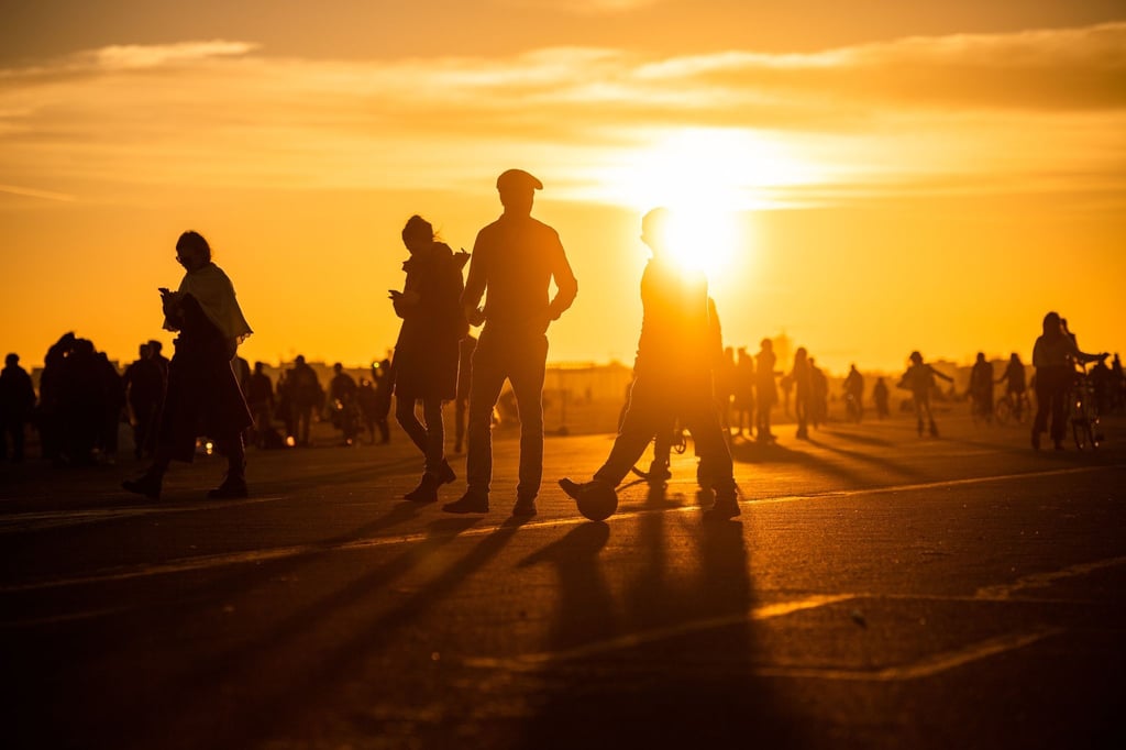 Menschen spazieren während des Sonnenuntergangs bei frühlingshaften Temperaturen auf dem Tempelhofer Feld.