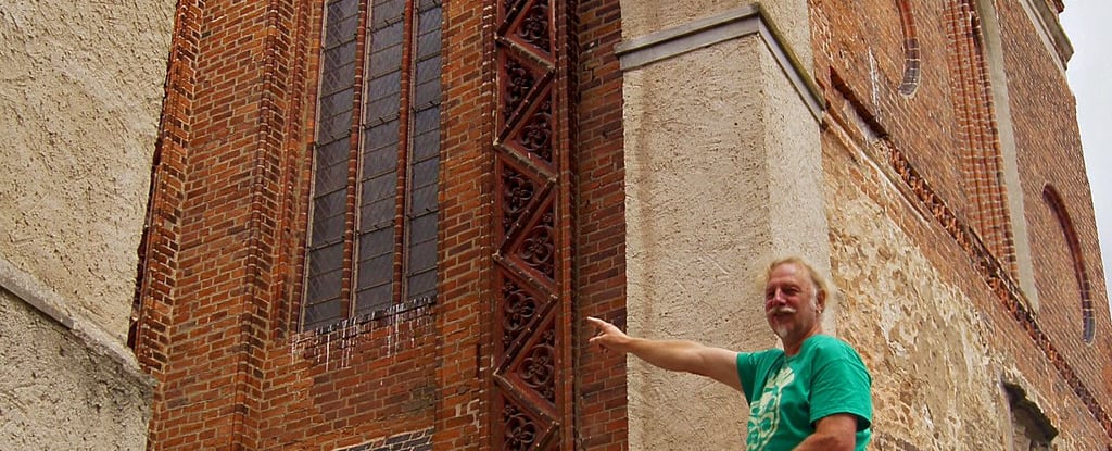 Museumsmitarbeiter Jörg Bonewitz zeigt, an welcher Stelle sich der Riss außen zeigt.