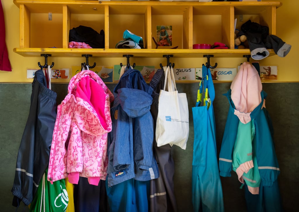 Kindersachen hängen an der Garderobe in einer Kita.