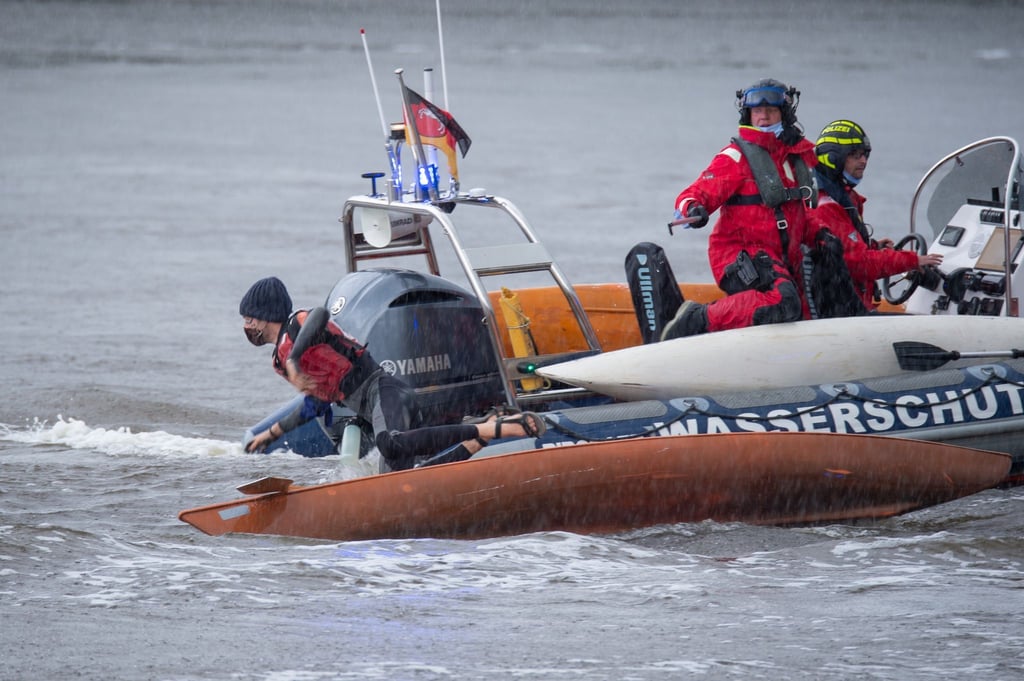 Eine Person springt von einem Kajak in das Fahrwasser des Nord-Ostsee-Kanals.