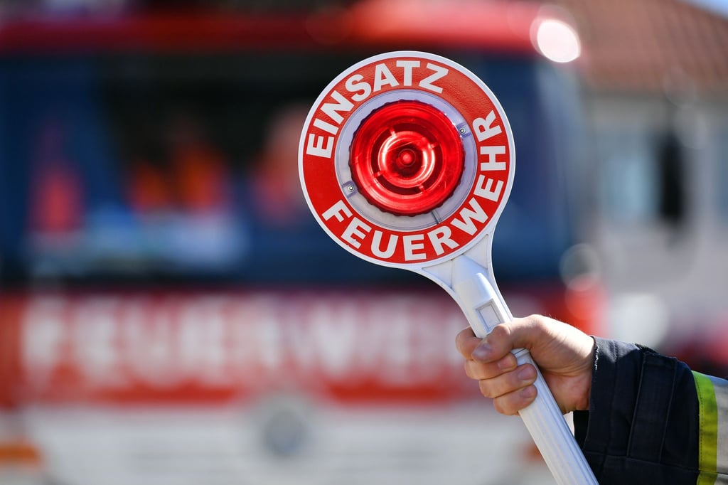 Ein Feuerwehrmann hält eine Winkerkelle mit der Aufschrift „Einsatz Feuerwehr“.