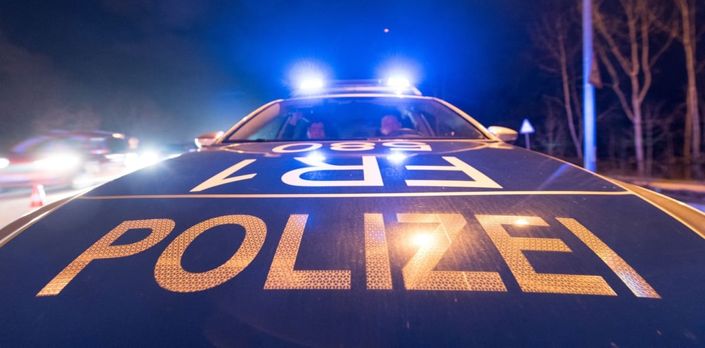 Ein Polizeifahrzeug steht mit leuchtendem Blaulicht auf der Straße.