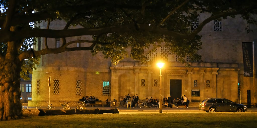Jugendliche sitzen am Abend vor dem Landesmuseum in Halle.