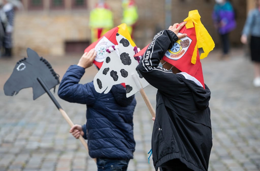 Mit ihren selbst gebastelten Steckenpferden "reiten" Grundschüler über den Markt.