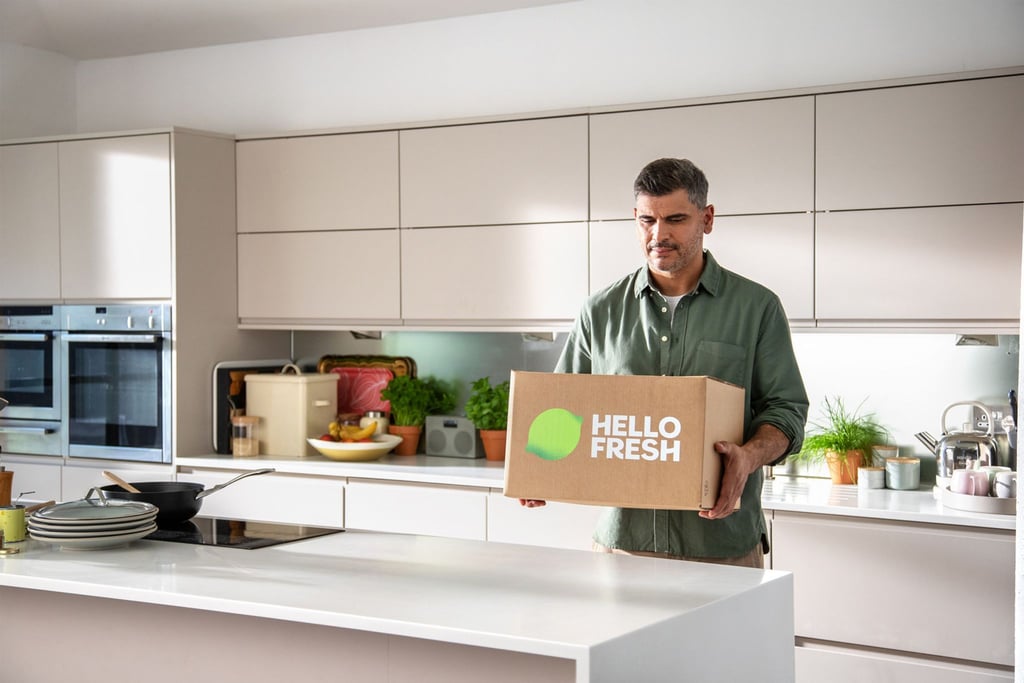 Ein Mann hält eine Box mit dem HelloFresh-Logo.