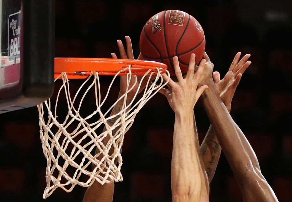 Spieler zweier Basketballmannschaften im Kampf um den Ball.