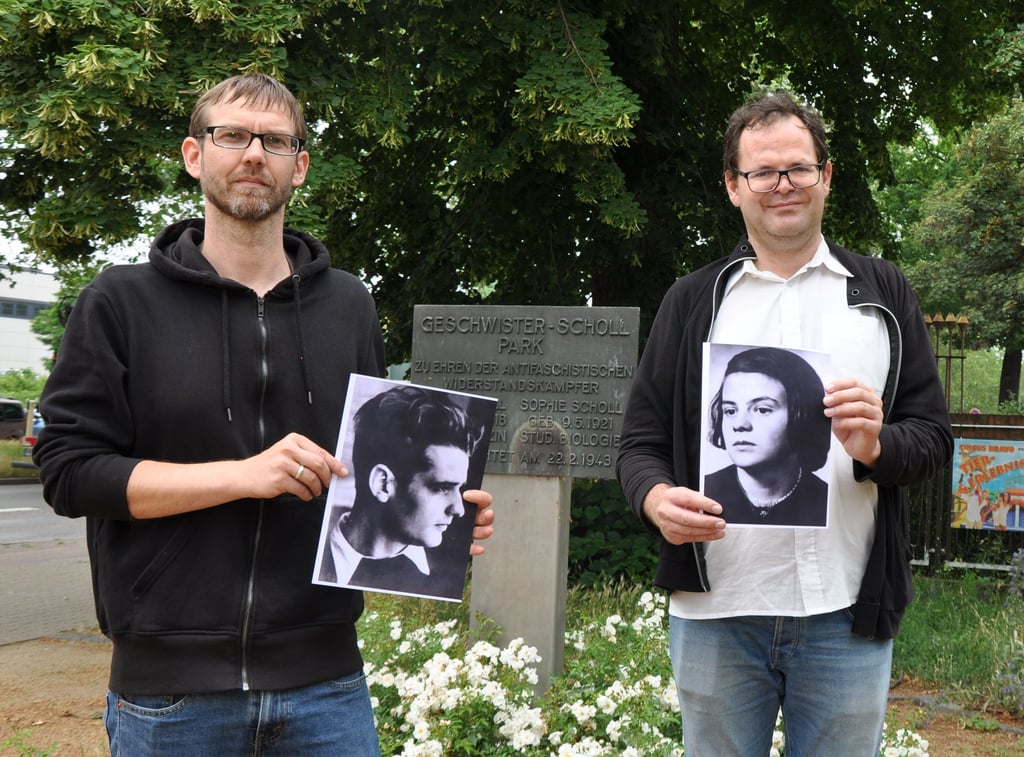 SPD-Stadtrat Christian Hausmann (rechts) mit einem Foto von Sophie Scholl und René Hempel (Linke) mit einem Foto von Hans Scholl vor der recht unauffälligen Stele am Rande des Geschwister-Scholl-Parkes in Magdeburg. Die beiden Stadträte wünschen sich den Bau einer künstlerisch gestalteten Erinnerungsstätte für die Namensgeber des Parks und haben den Stadtrat dafür einstimmig an ihrer Seite.