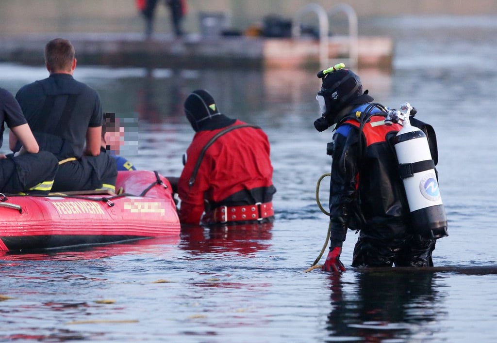 Taucher der Feuerwehr suchen einen See ab.