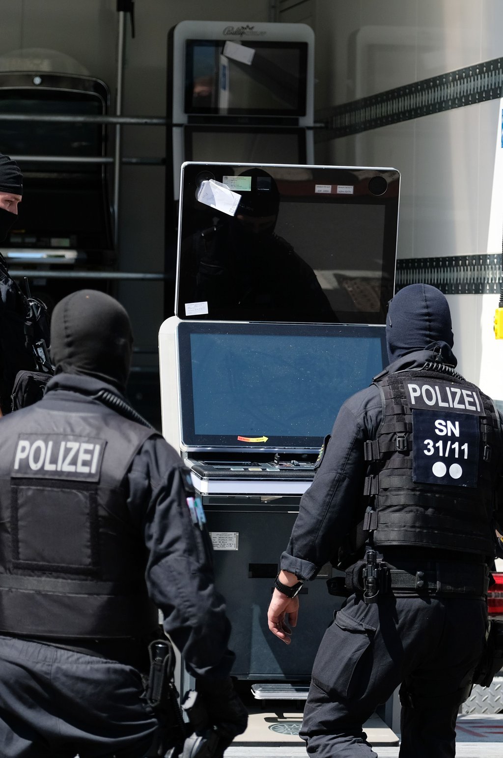Polizisten transportieren sichergestellte Spielautomaten aus einer Shishabar.