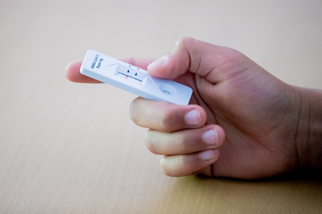 Ein Schüler hält einen Antigen-Schnelltest in der Hand.