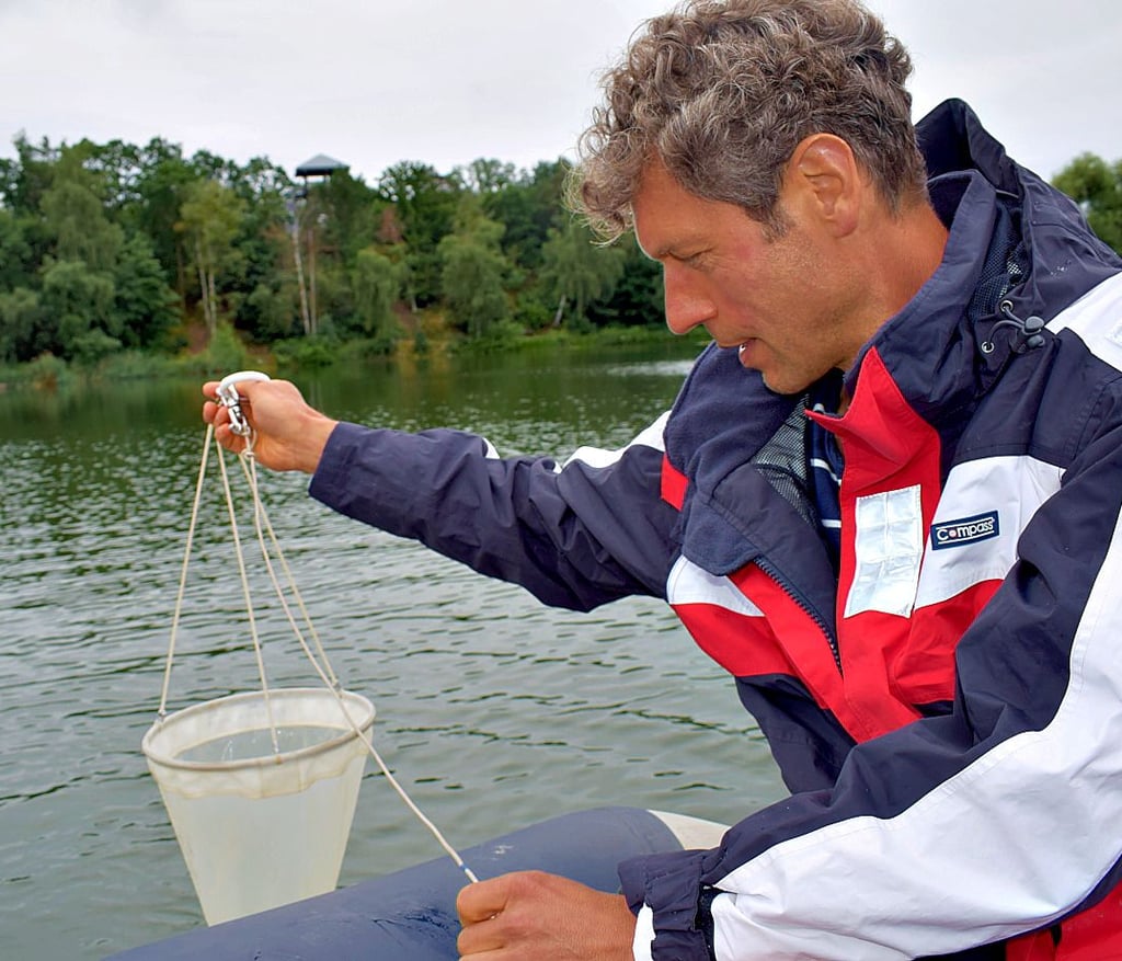 Dr. Karsten Rinke nimmt das Planktonnetz aus dem Wasser. Der Inhalt wurde ebenfalls in ein Probenglas gefüllt.