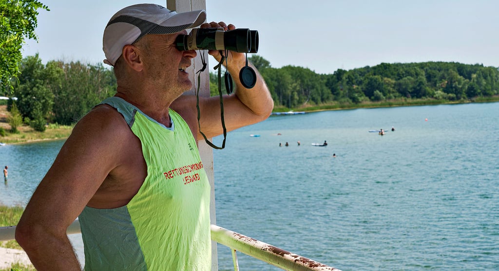Reinhard Vogler überwacht das Badegeschehen am Jersleber See. Mit seinem Fernglas hat er stets den Überblick. Glücklicherweise kommt es nur selten zu Badeunfällen an dem vielbesuchten Gewässer.