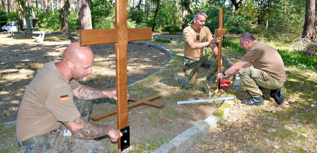 Stabsfeldwebel René Gebhardt, Hauptmann Jens Meiering und Stabsfeldwebel Sven Panther (von links) montieren die Kreuze auf dem Klietzer Ehrenfriedhof.