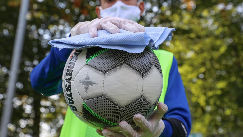 Ein Helfer säubert den Fußball vor einem Spiel mit Desinfektionsmittel.