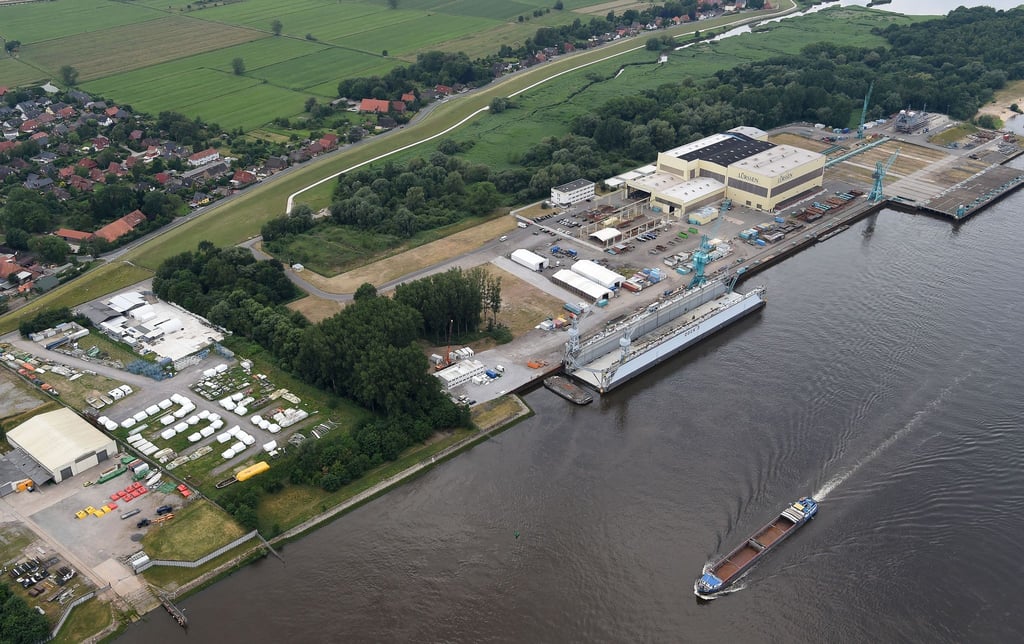 Die Luftaufnahme zeigt ein Schiff das auf der Weser an der Lürssen Werft vorbei fährt.
