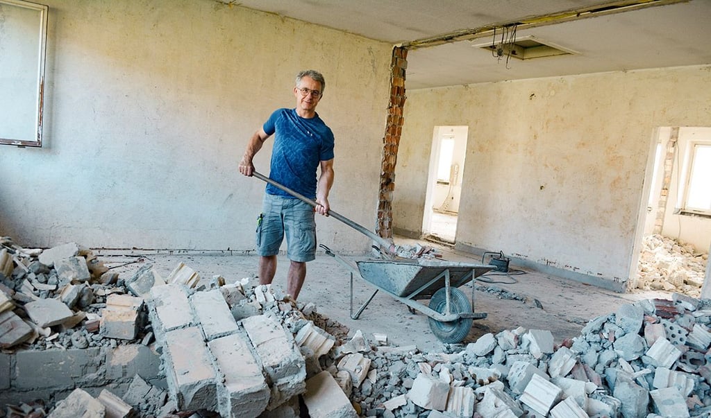 Klaus Oertel lädt Schutt im Obergeschoss in eine Schubkarre.