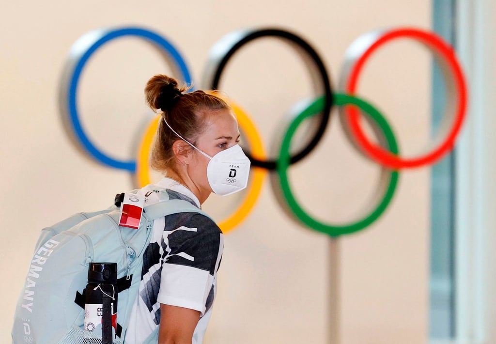 Eine deutsche Athletin trägt eine Schutzmaske und geht bei ihrer Ankunft am Flughafen Haneda an den Olympischen Ringen vorbei.