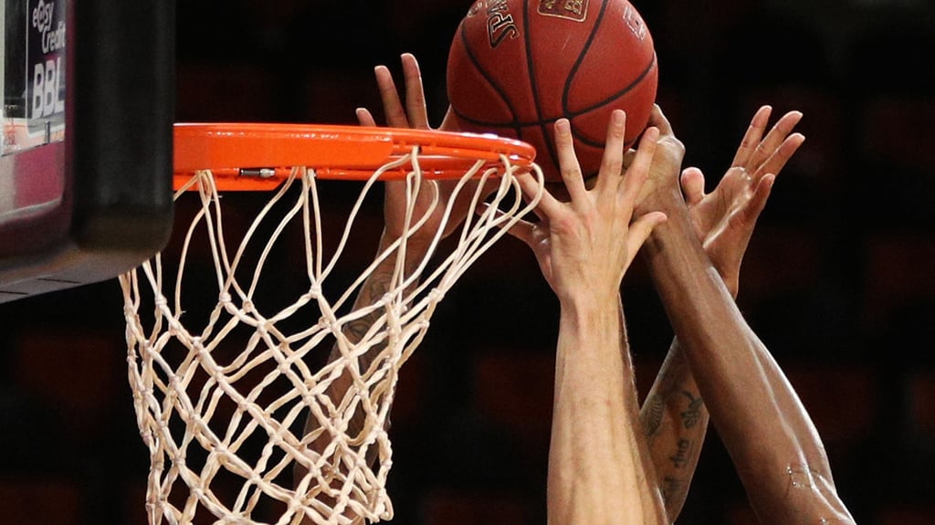 Spieler zweier Basketballmannschaften im Kampf um den Ball.