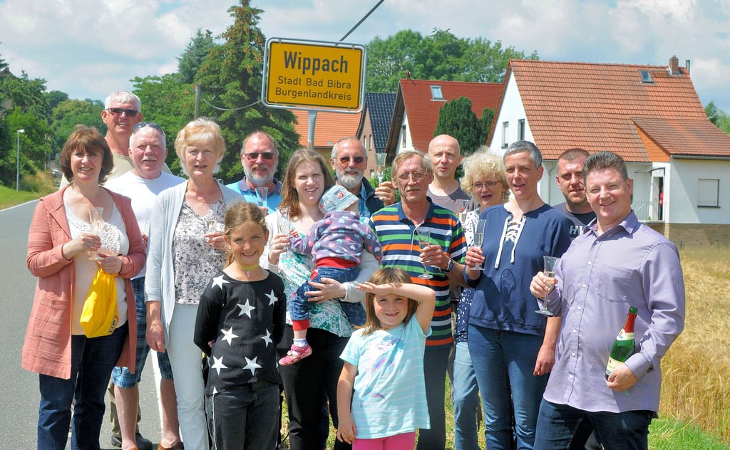 Vorstand und einige Mitglieder des neugegründeten Vereins stoßen am Wippacher Ortseingangsschild mit Sekt an.