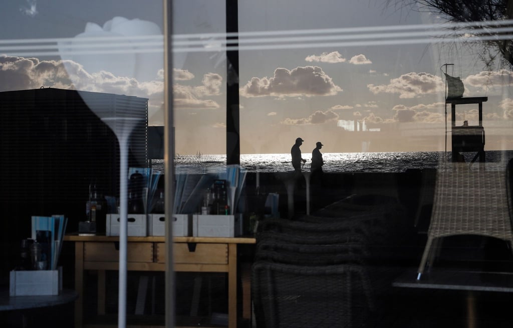 Menschen spiegeln sich im Fenster einer geschlossenen Bar in der Schinkenstraße auf Palma.