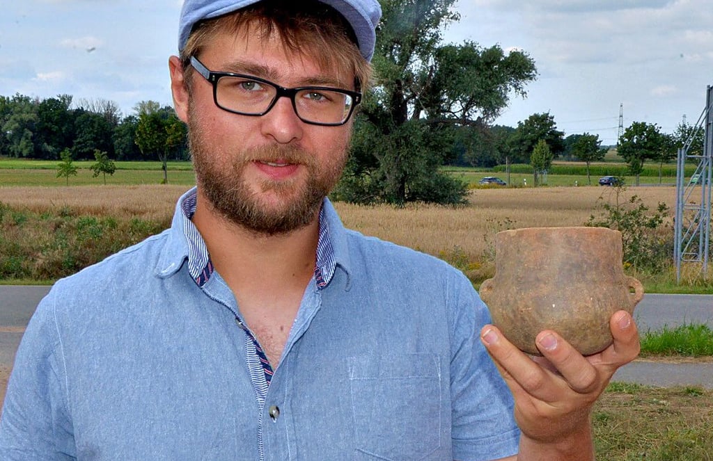 Nikita Sirman präsentiert ein gut erhaltenes bronzezeitliches Trinkgefäß. Die Archäologen fanden außerdem Scherben und Knochen.