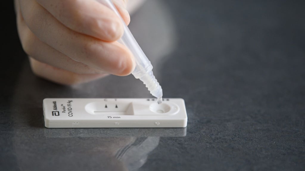 Eine Lösung wird auf eine Testkassette eines Corona-Schnelltests aufgeträufelt.