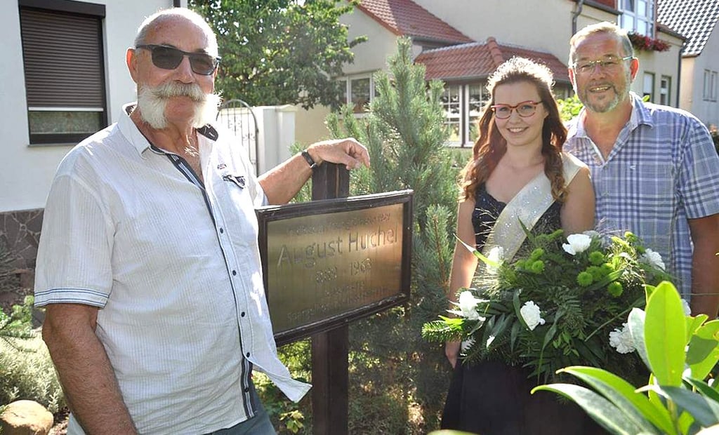  Klaus-Peter Gose (links), die damalige Osterburger Spargelkönigin Katarina Rodenbeck und Thorsten Schulz im August 2019 vor Huchels einstigem Wohnhaus. Schulz hatte die Idee für ein Spargel-Denkmal, die von Gose von Anfang an unterstützt wurde.