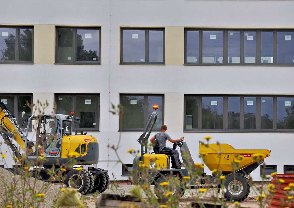 Sanierung für das Edithagymnasium Magdeburg: Vor der bereits fertiggestellten Fassade des Gebäudes A sind Baufahrzeuge unterwegs. Hier geht es zurzeit um den Bau der Freiflächen.