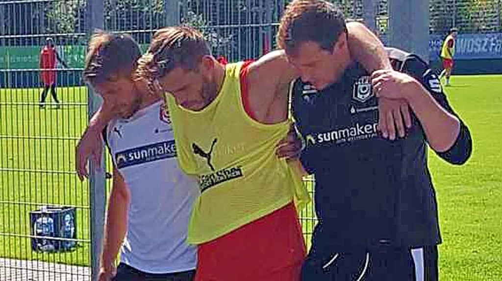 Justin Eilers hat sich beim HFC-Training verletzt und wird von Ken Kaiser und Physio Florian Thiele (r.) vom Platz begleitet.