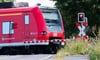 Eine S-Bahn der Deutschen Bahn (DB) fährt an einem Bahnübergang mit einer roten Ampel vorbei.