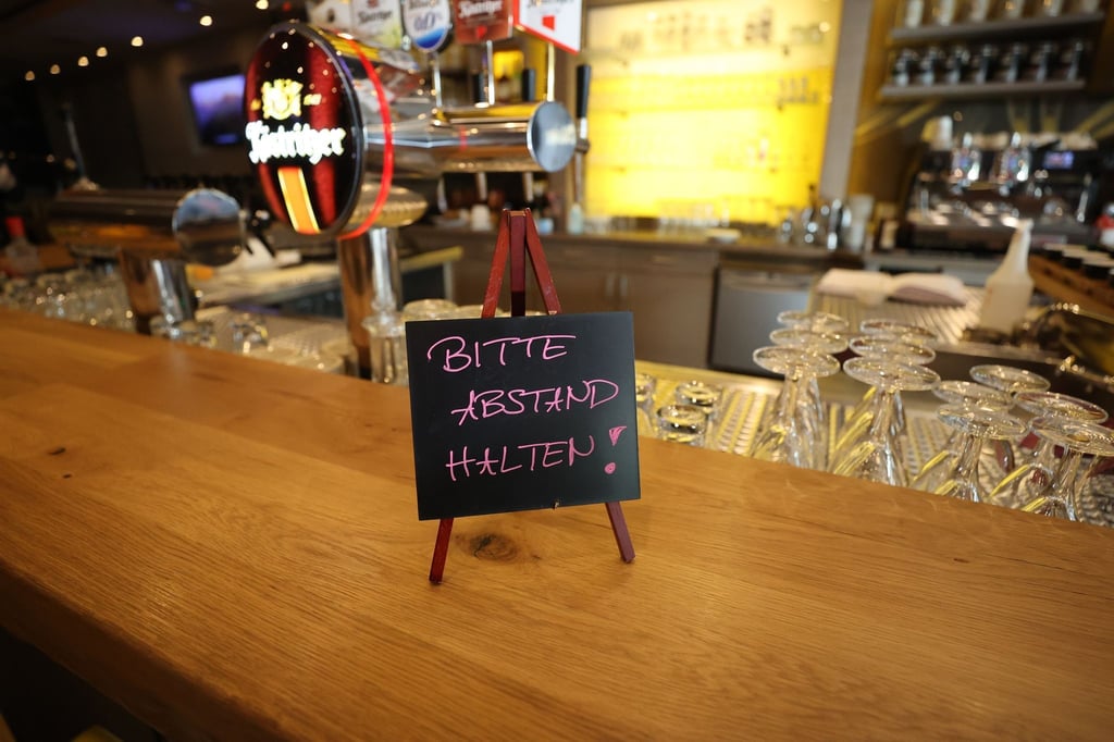 Ein Schild mit der Aufschrift "Bitte Abstand halten" steht auf dem Tresen in einem Bierhaus.