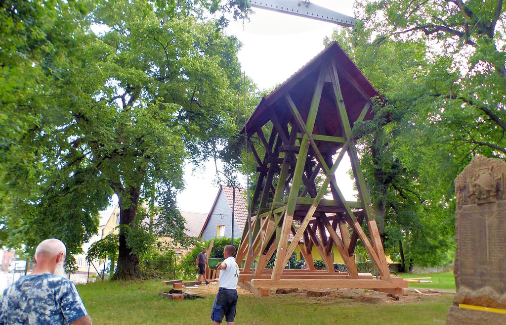 Der rund vier Tonnen schwere Glockenstuhl neben der Rösaer Kirche  hängt am Haken des Kranes.