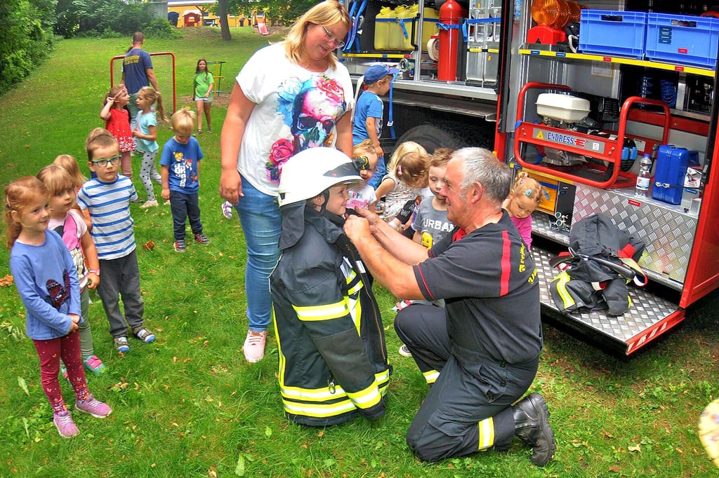 Volker Ollendorf von der Freiwilligen Feuerwehr Hornhausen steckt den kleinen Johann in die doch noch ein wenig zu große Montur.