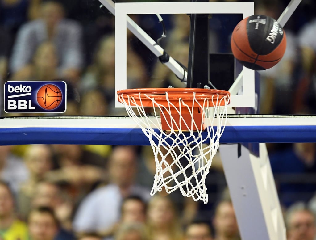 Ein Basketball fliegt in den Korb.
