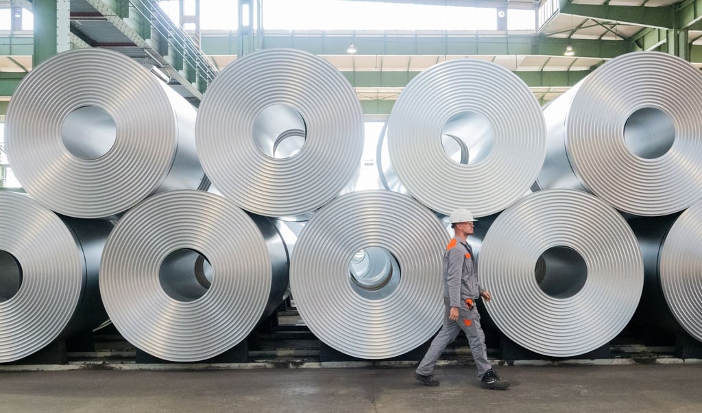 Ein Mitarbeiter geht bei der Salzgitter AG an aufgewickeltem Stahl (Coils) vorbei.
