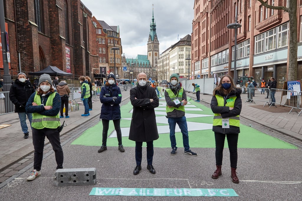 Peter Tschentscher (2.v.l., SPD), Erster Bürgermeister von Hamburg, sowie Aktivisten von Fridays for Future stehen vor dem Schriftzug „WIR ALLE FÜR 1,5 GRAD„ in der Mönckebergstraße.