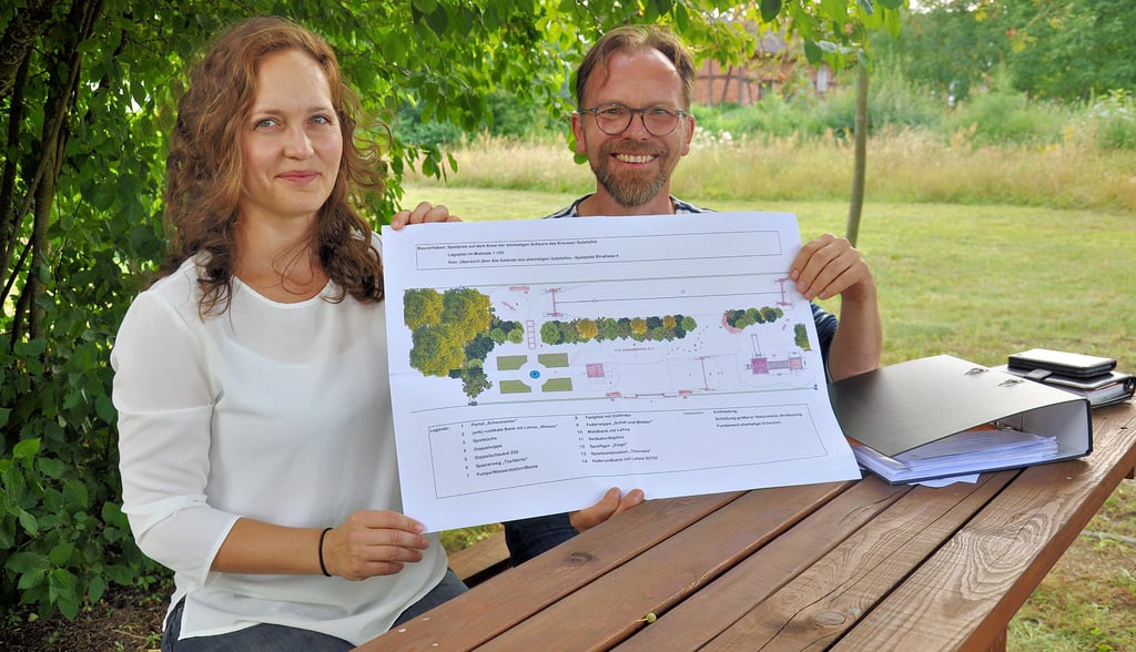 Juliane Meutzner und Ralf Engelkamp zeigen auf dem Gutshof in Krevese die Projektzeichnung einer ?Spielscheune?, die auf dem Grün im Hintergrund Gestalt annehmen soll.