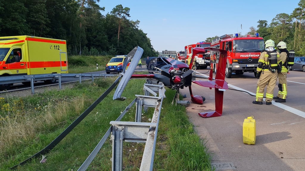 Einsatzkräfte der Feuerwehr stehen an der Absturzstelle eines Tragschraubers
