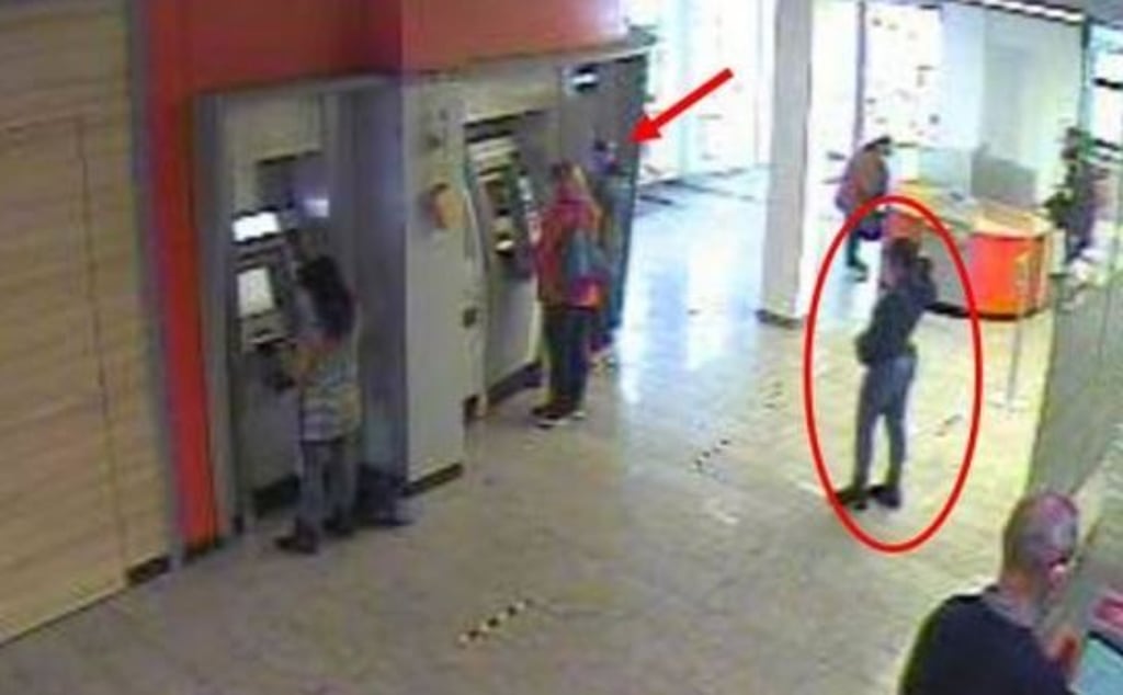 Gegen 10.17 wartet eine mutmaßliche Täterin (roter Pfeil) neben einem Geldautomaten, da beide belegt sind und sucht augenscheinlich etwas. Die vermeintliche Komplizin wartet dahinter (roter Kreis).