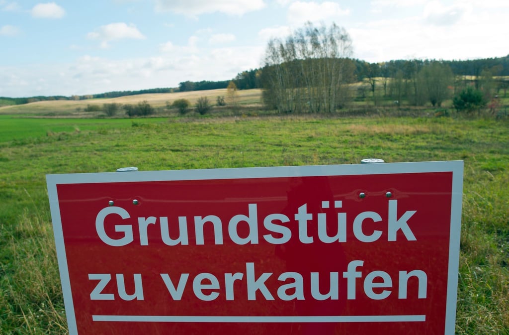 Ein Schild mit der Aufschrift „Grundstück zu verkaufen“ steht an einer Straße.