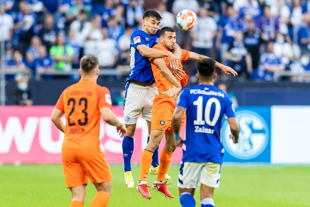 Schalkes Mehmet Aydin (2.v.l.) und Aues Soufiane Messequem (2.v.r.) gehen zum Kopfballduell hoch.