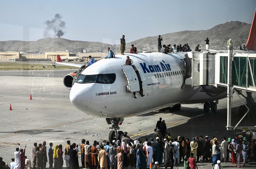 Menschen versuchen sich am Flughafen Kabul an ein Flugzeug zu klammern.