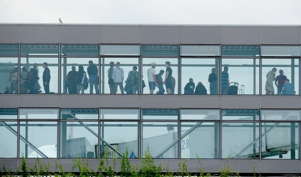 Passagiere stehen am Flughafen Leipzig-Halle in einem Wartebereich.