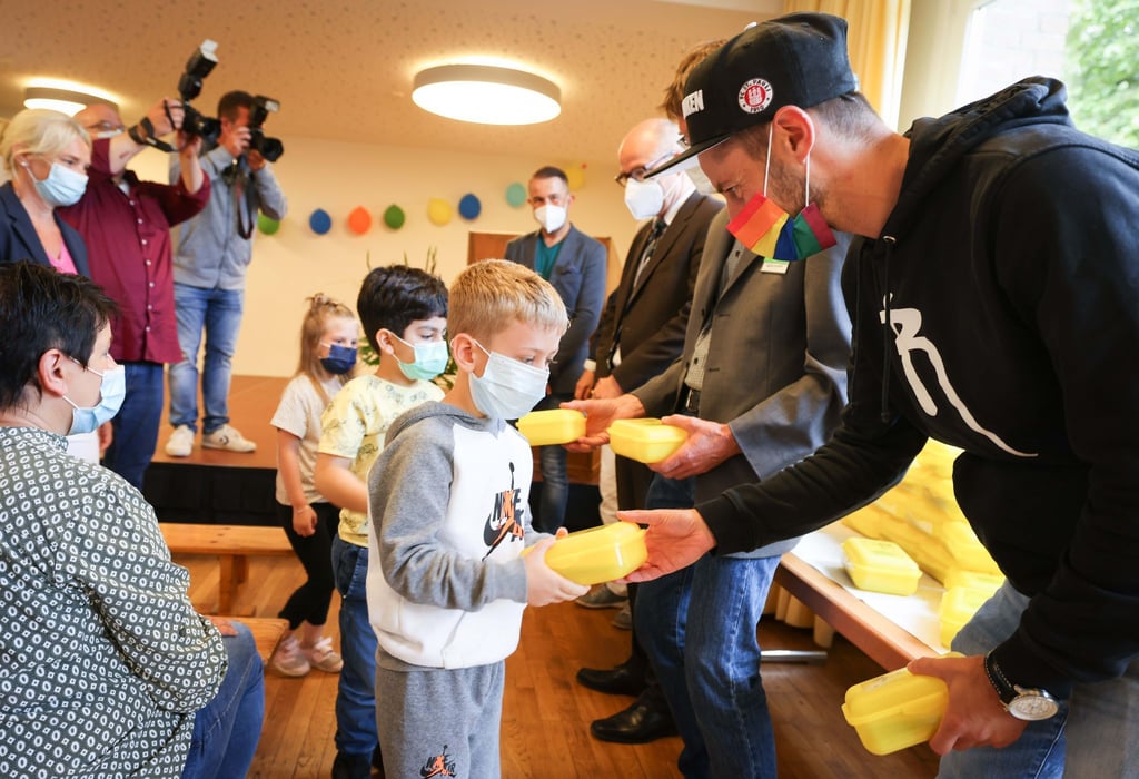 Jan-Philipp Kalla (r) verteilt Bio-Brotboxen an Erstklässler.