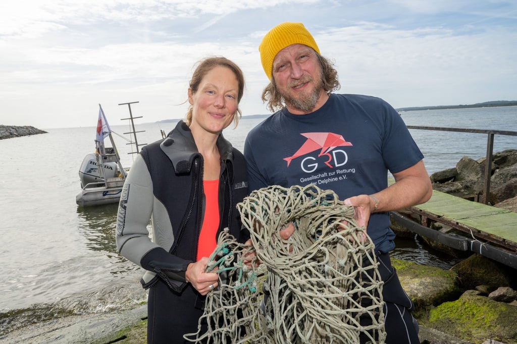Das Schauspieler-Paar Tessa Mittelstaedt (47) und Matthias Komm (54) steht vor einem Tauchgang in die Ostsee vor der Insel Rügen an der Tauchbasis Mukran mit einem Netz in der Hand da.