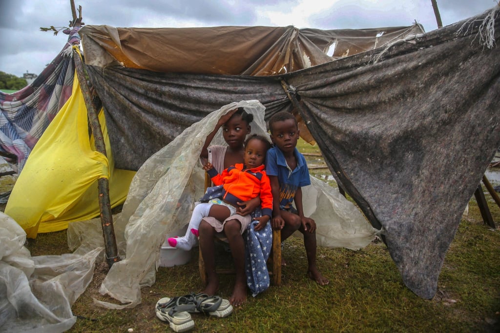 Kinder versuchen in Les Cayes, sich mit einer Plane vor dem Regen zu schützen.